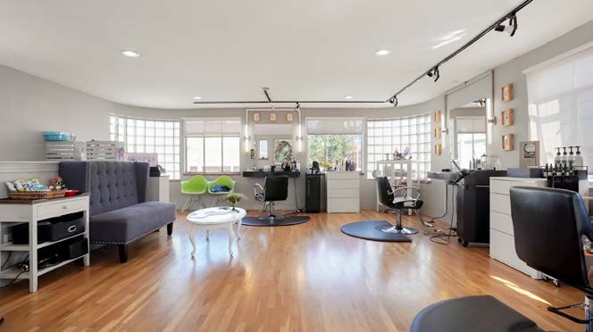 Bright room with curved glass-block corners, currently set up with salon stations