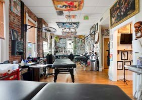 Inside Think Tank Tattoo South: tattoo stations in a brick-walled studio hung with artwork
